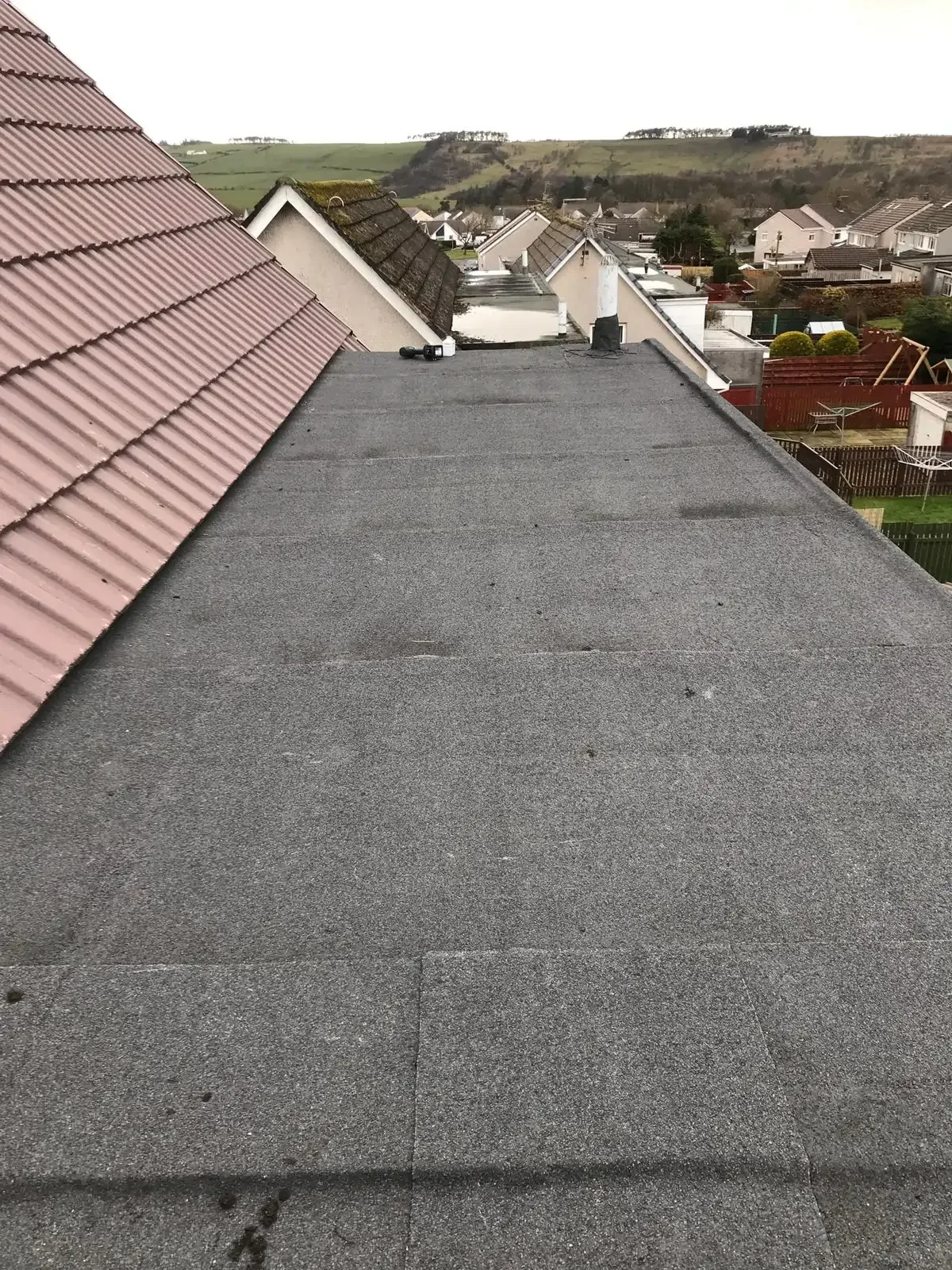 Completed grey felt flat roof extension alongside a tiled pitched roof