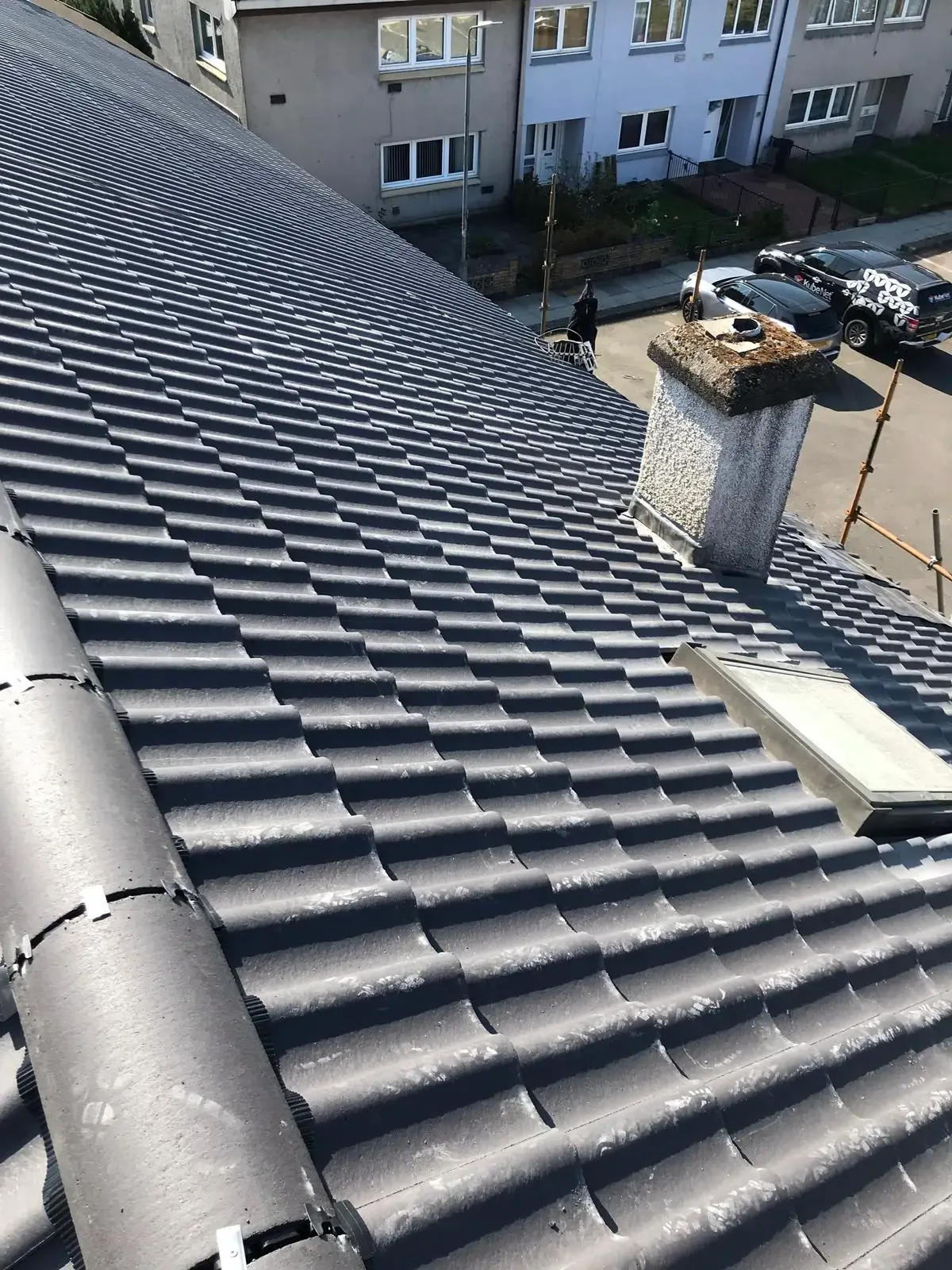 Newly completed grey tiled roof with a rendered chimney stack