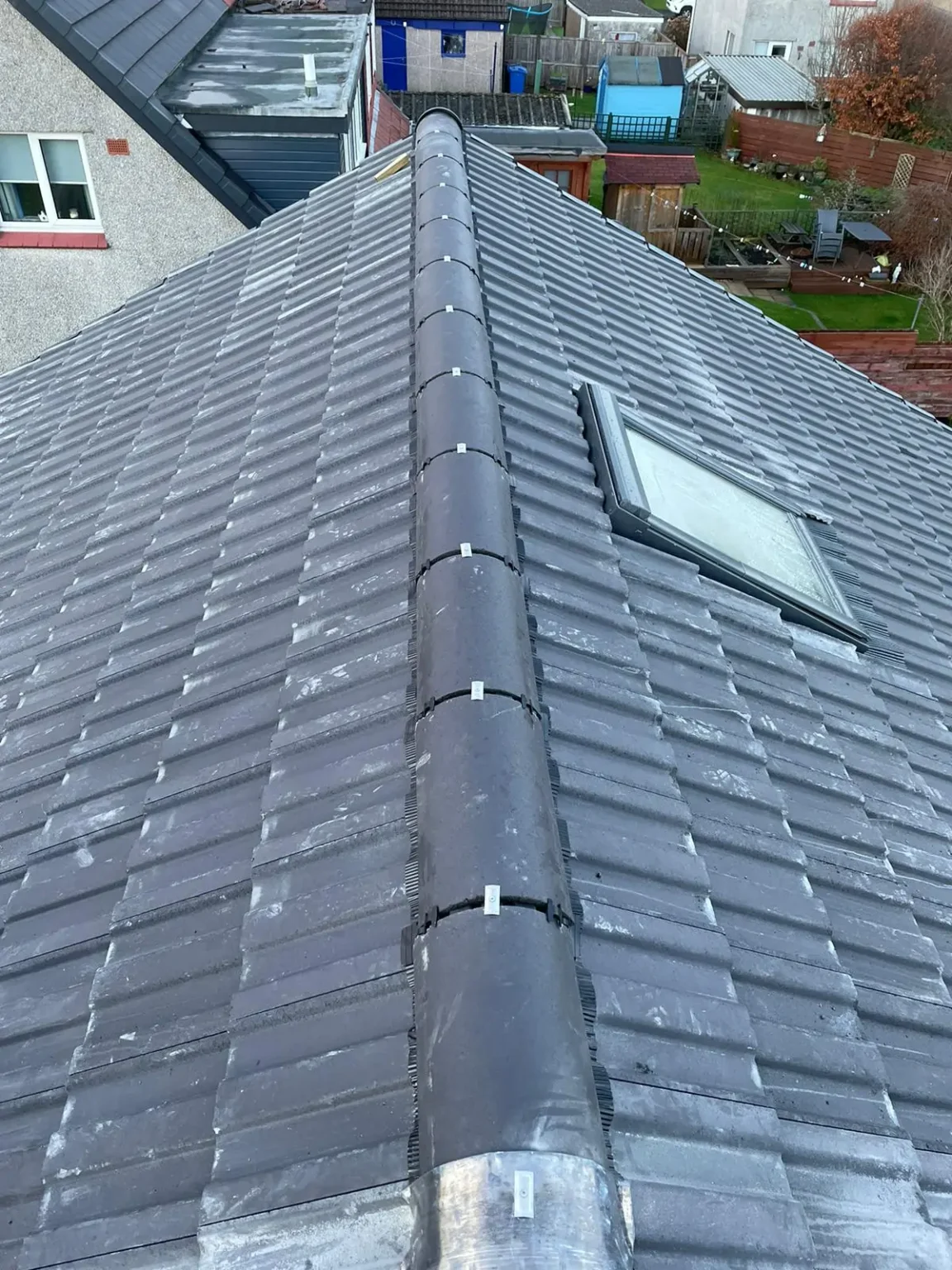 Roofing company Glasgow completing tiled roof installation with ridge tiles and roof window on residential property